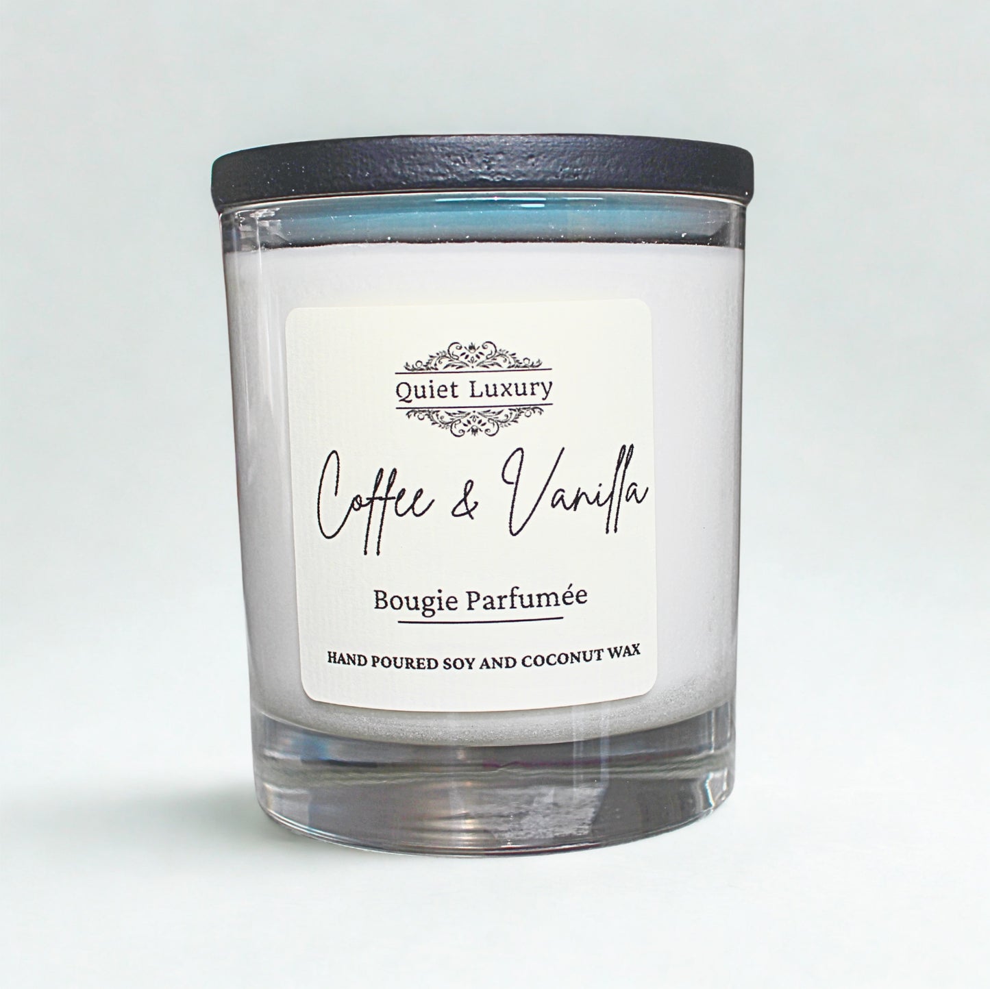 Candle with a label reading 'Coffee & Vanilla' by 'Quiet Luxury' on a light gray background.