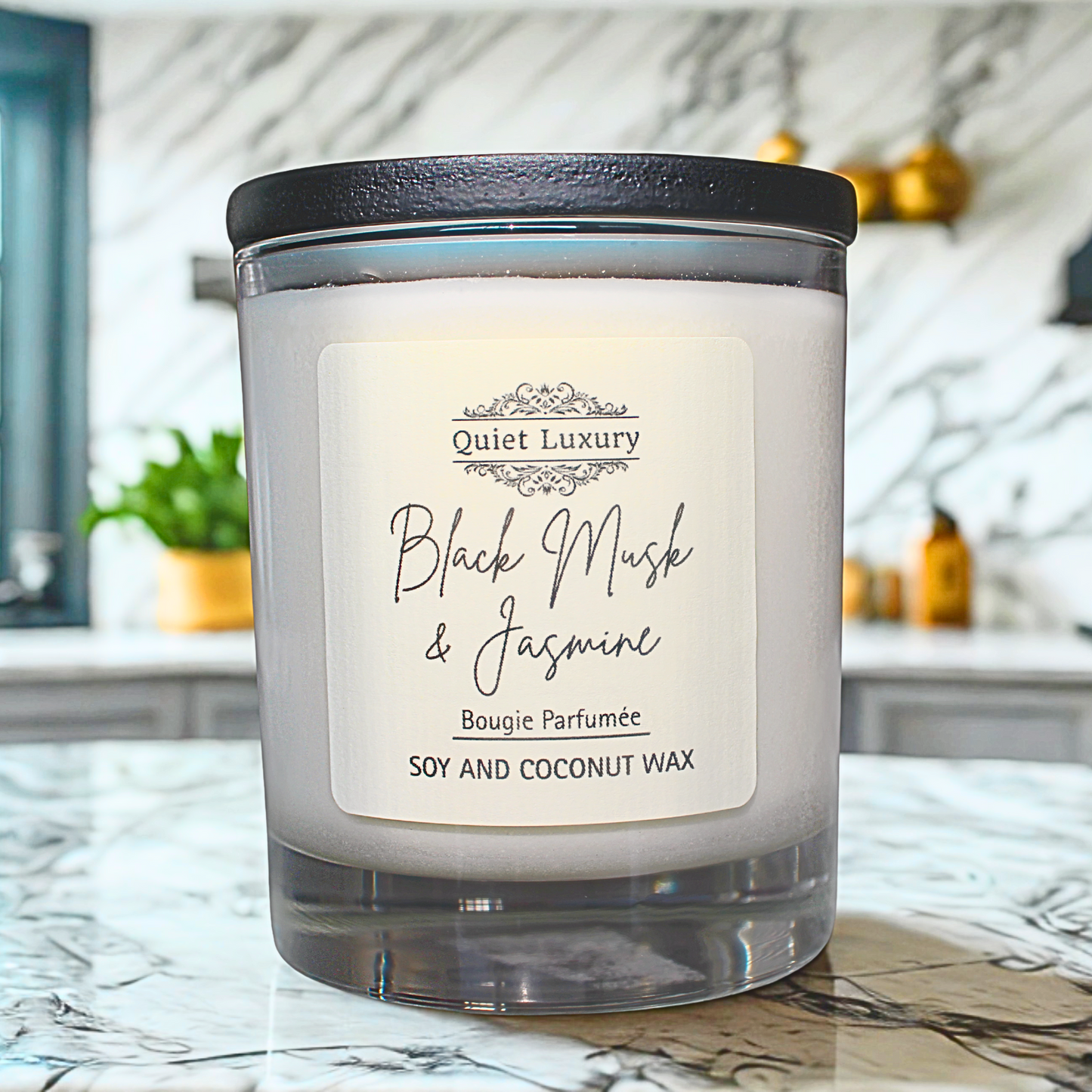 Candle labeled 'Quiet Luxury Black Musk & Jasmine' on a marble surface