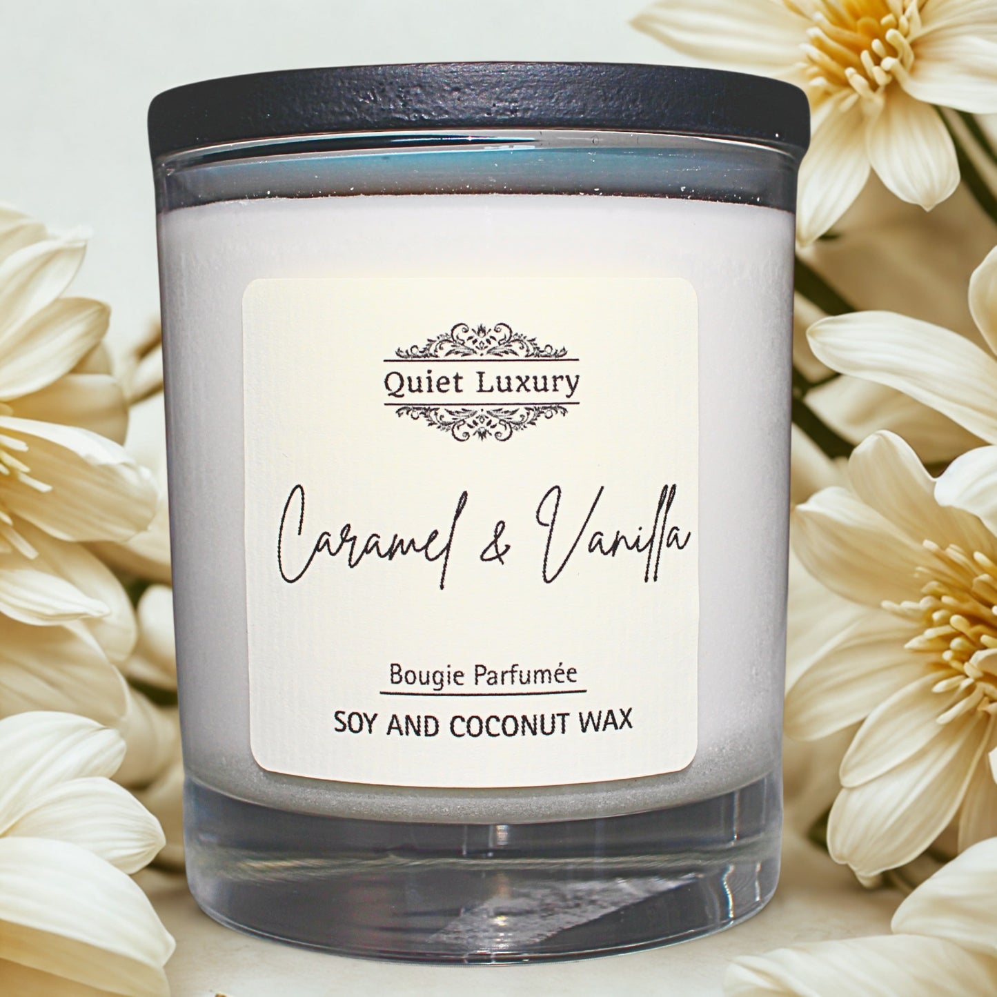 Candle labeled 'Quiet Luxury' with 'Caramel & Vanilla' on a white background with flowers.