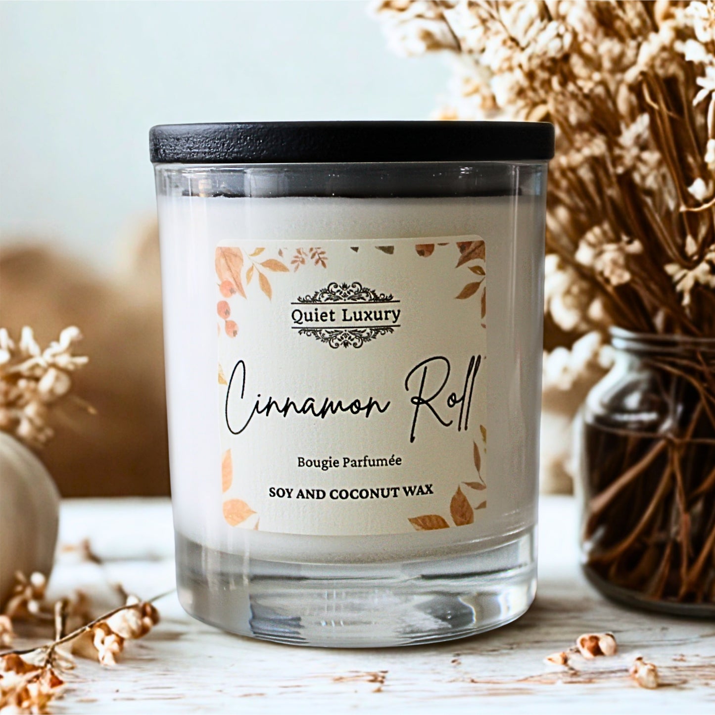 Candle labeled 'Cinnamon Roll' by 'Quiet Luxury' autumn candle