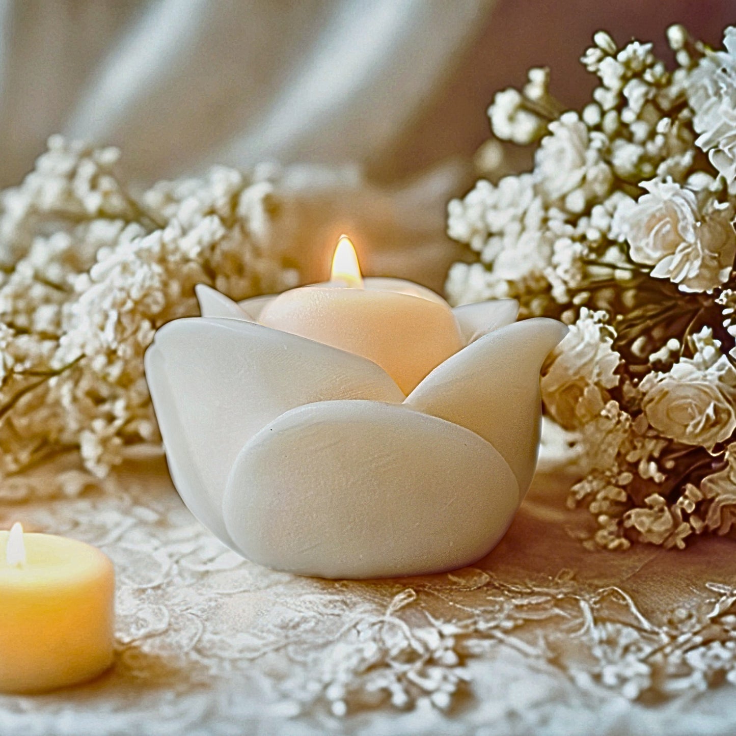 Whitesoy wax favour candle with a lit candle surrounded by white flowers on a soft background