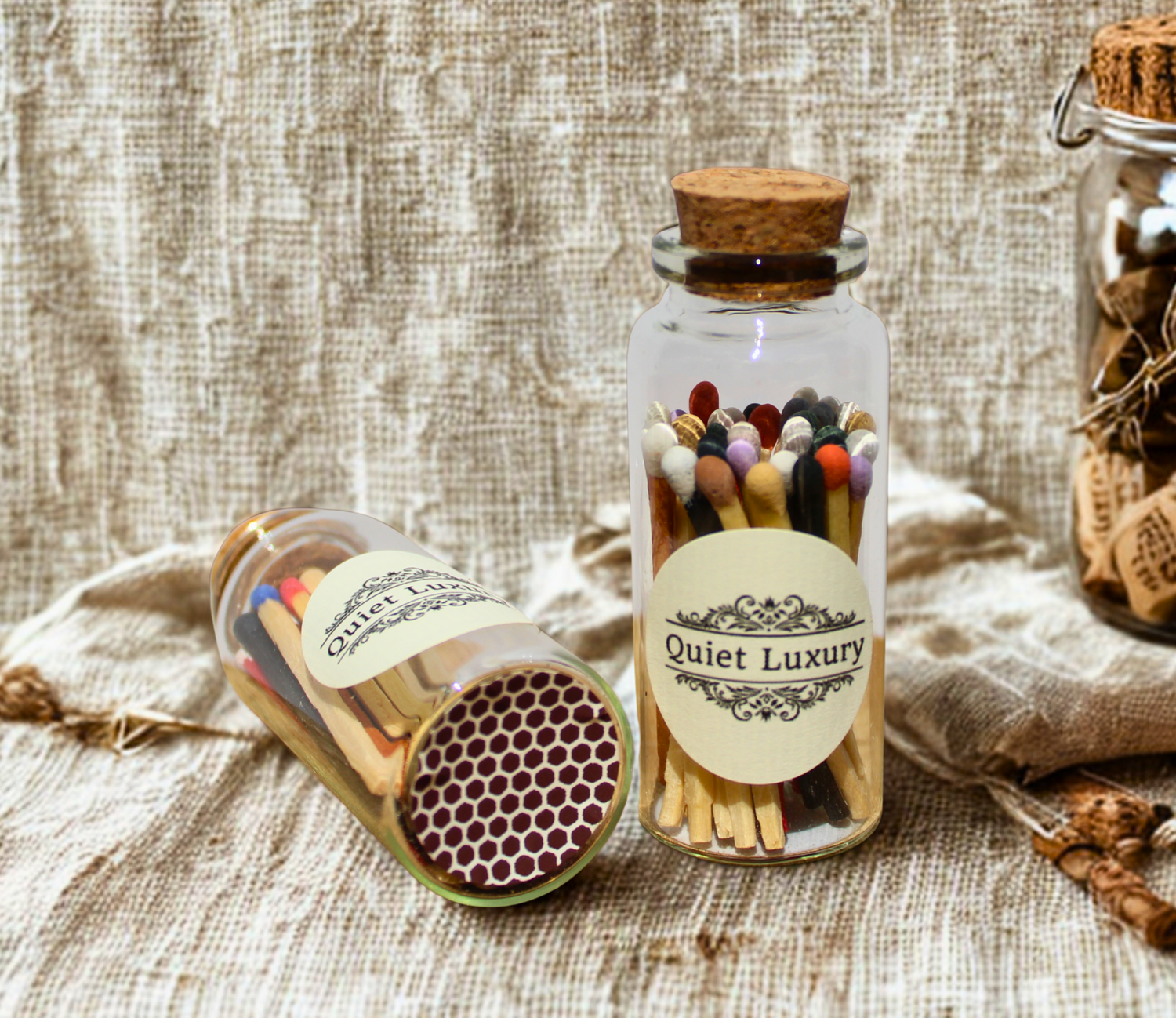 Glass jars of coloured matches with cork lids and vintage label on rustic linen