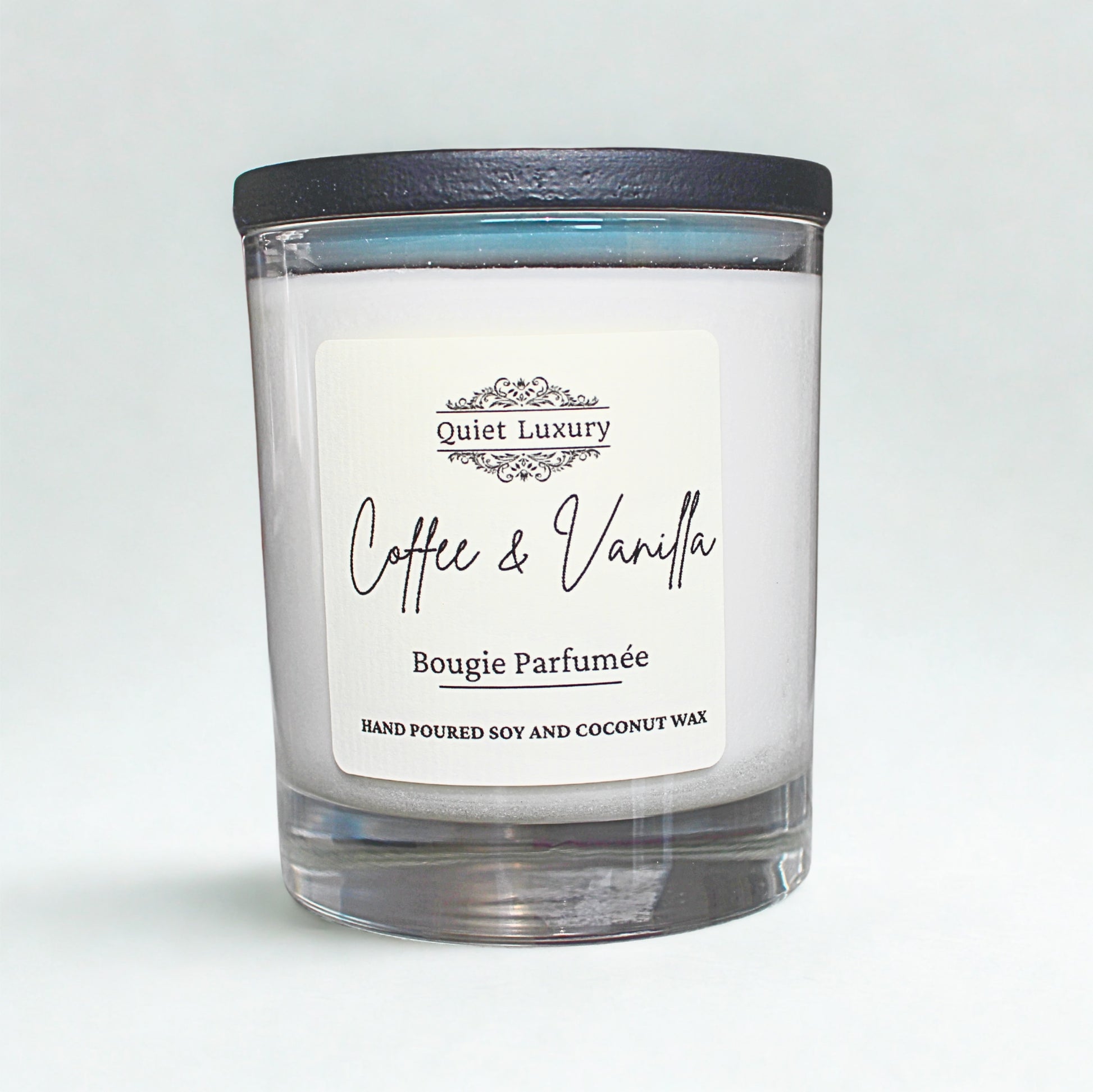 Candle with a label reading 'Coffee & Vanilla' by 'Quiet Luxury' on a light gray background.