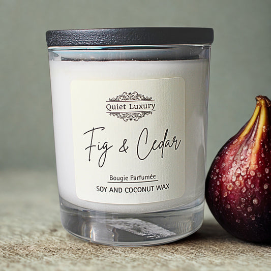 Candle labeled 'Fig & Cedar' by Quiet Luxury with a fig next to it on a neutral background