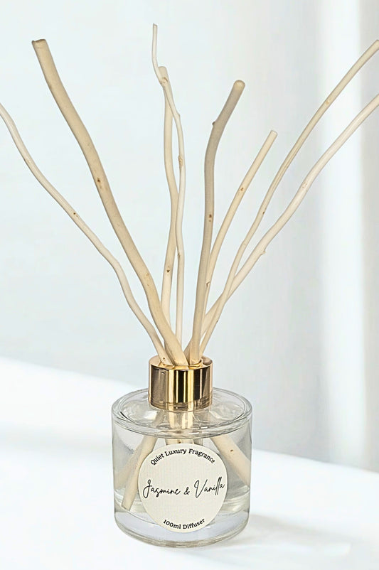 Clear diffuser with gold cap and wooden willow reed sticks on a white background