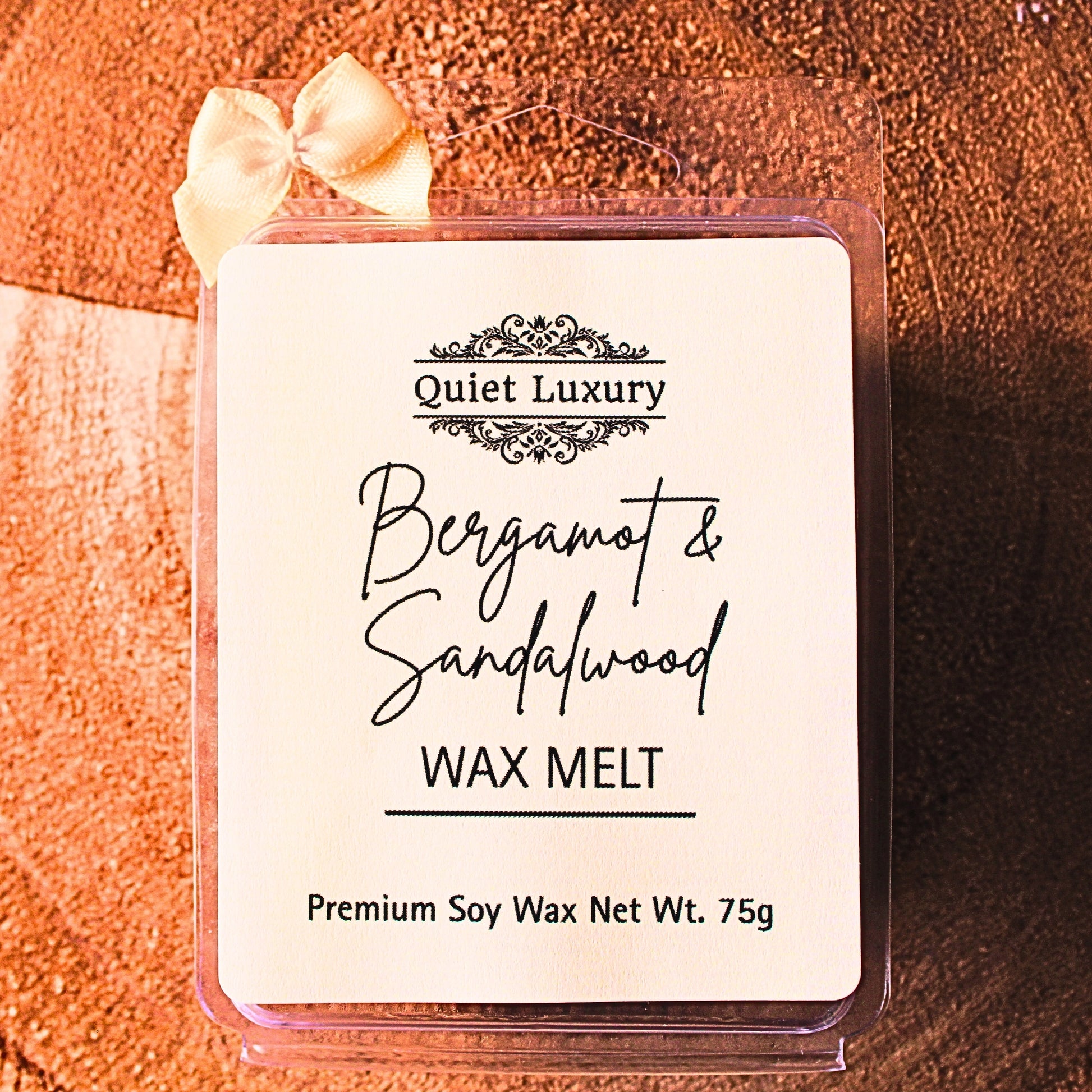 bergamot and sandalwood soy wax melt packaging with 'Quiet Luxury' branding on a textured surface