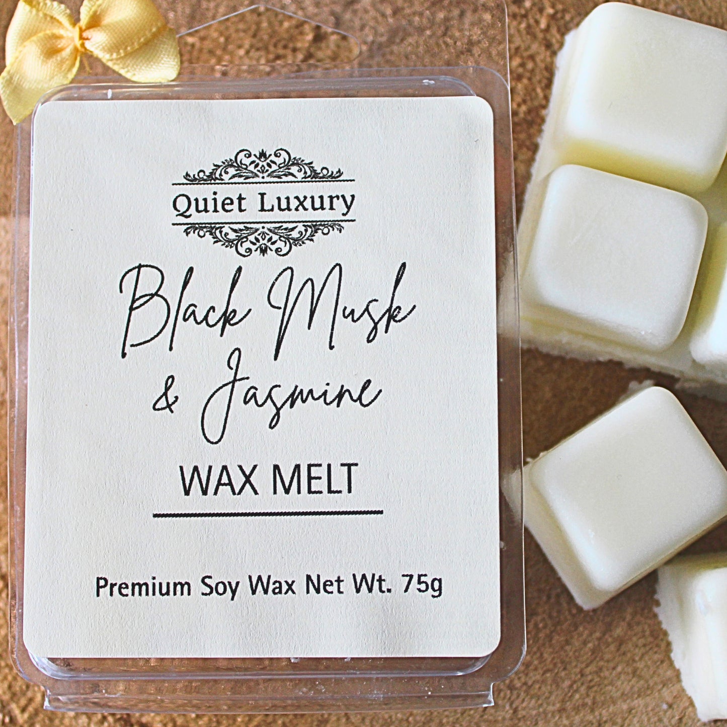 black musk and jasmine soy wax melt packaging with 'Quiet Luxury' branding and product name on a wooden surface.