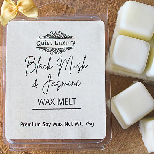 black musk and jasmine soy wax melt packaging with 'Quiet Luxury' branding and product name on a wooden surface.