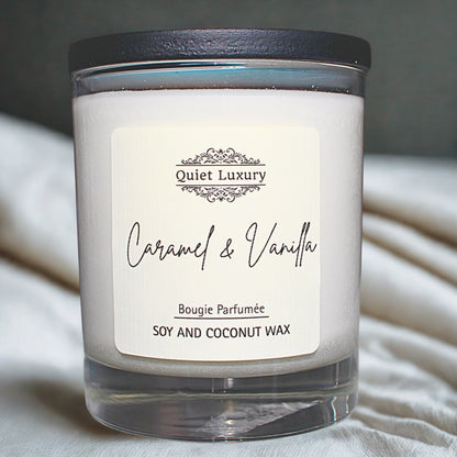 Caramel and vanilla soy and coconut wax candle in a clear glass jar on a soft white fabric.