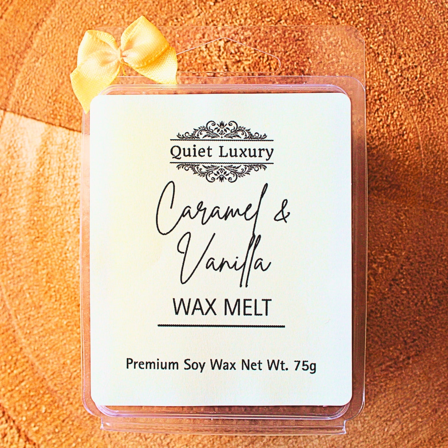Caramel & Vanilla soy wax melt packaging with 'Quiet Luxury' branding on a wooden background.