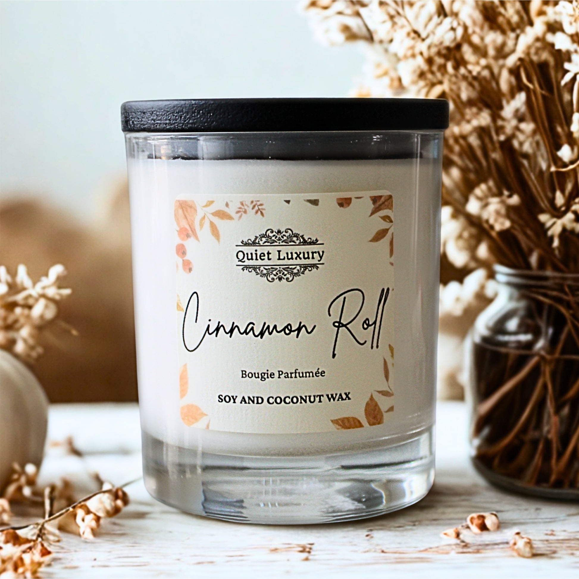 Candle labeled 'Cinnamon Roll' by 'Quiet Luxury' autumn candle