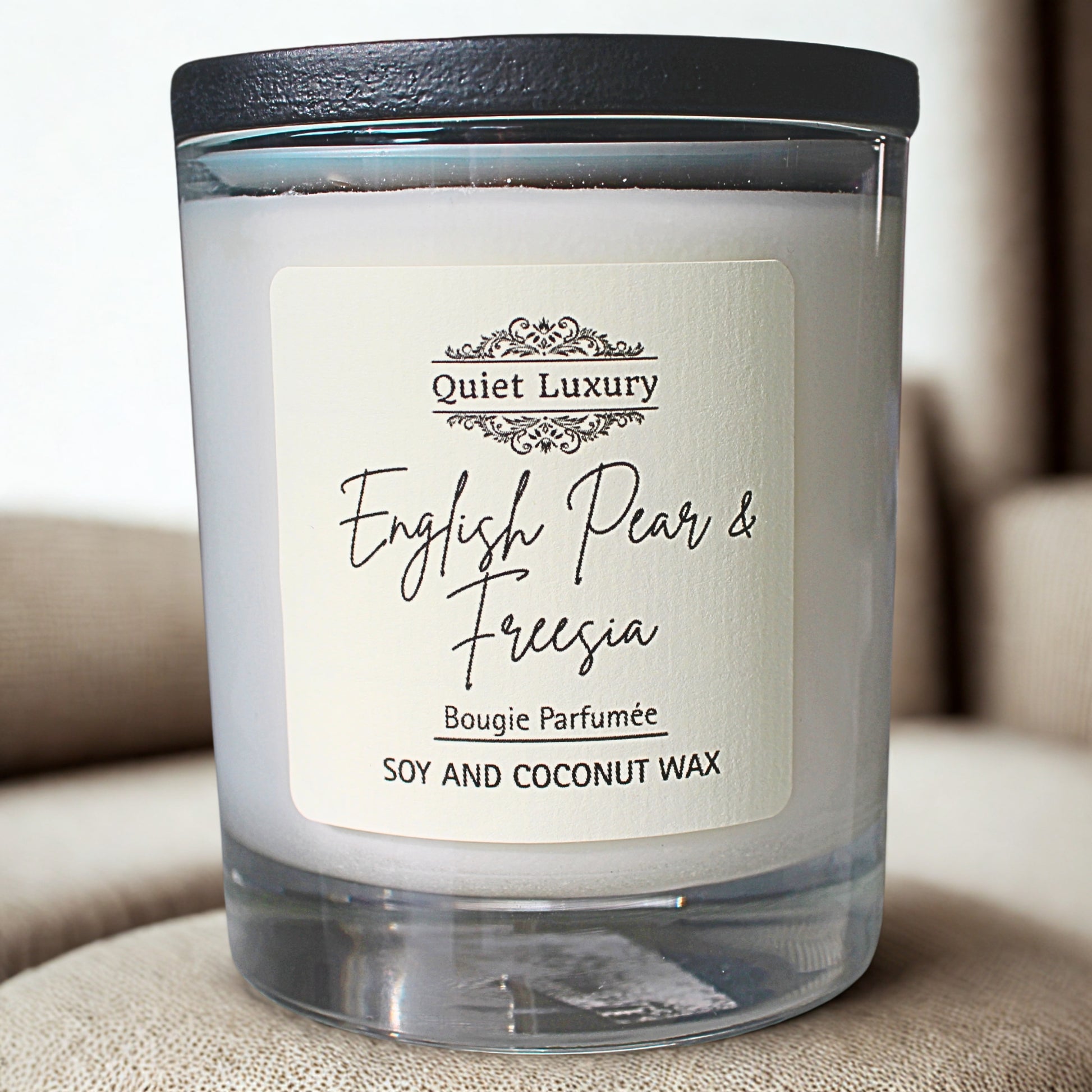 English pear and freesia Candle with 'Quiet Luxury' label on a beige surface