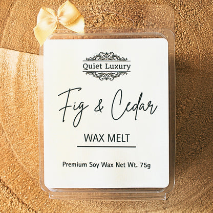 Fig and cedar soy wax melt in clear packaging with a gold bow on a wood background