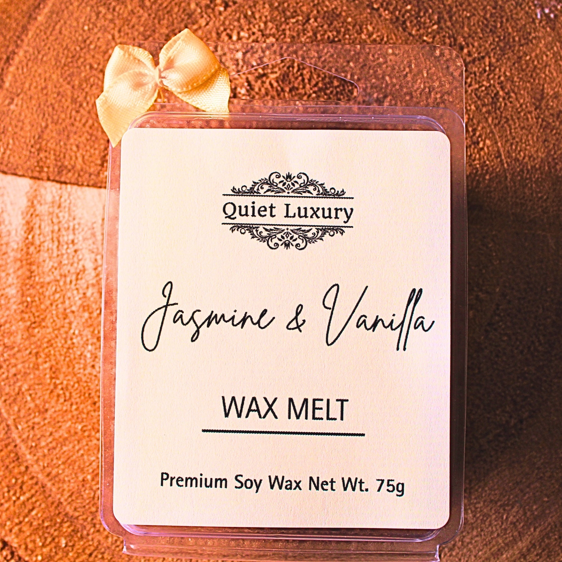 Jasmine and vanilla wax melt packaging with 'Quiet Luxury' branding on a wooden surface