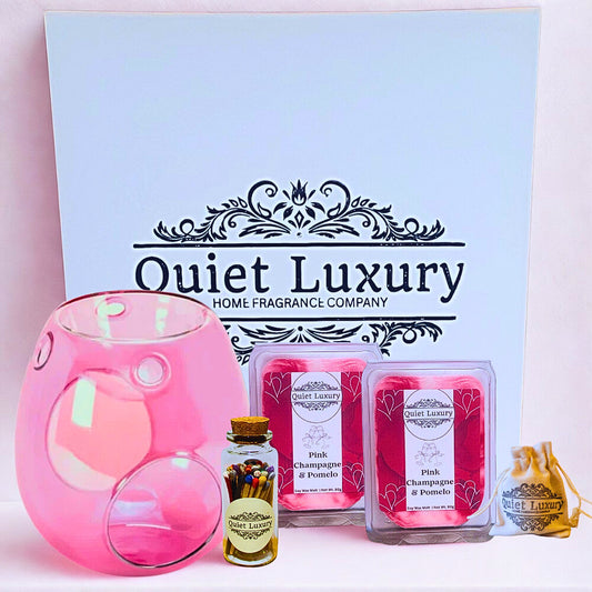 Pink wax warmer, luxury coloured matches, and wax melts with 'Quiet Luxury' branding on a light pink background.