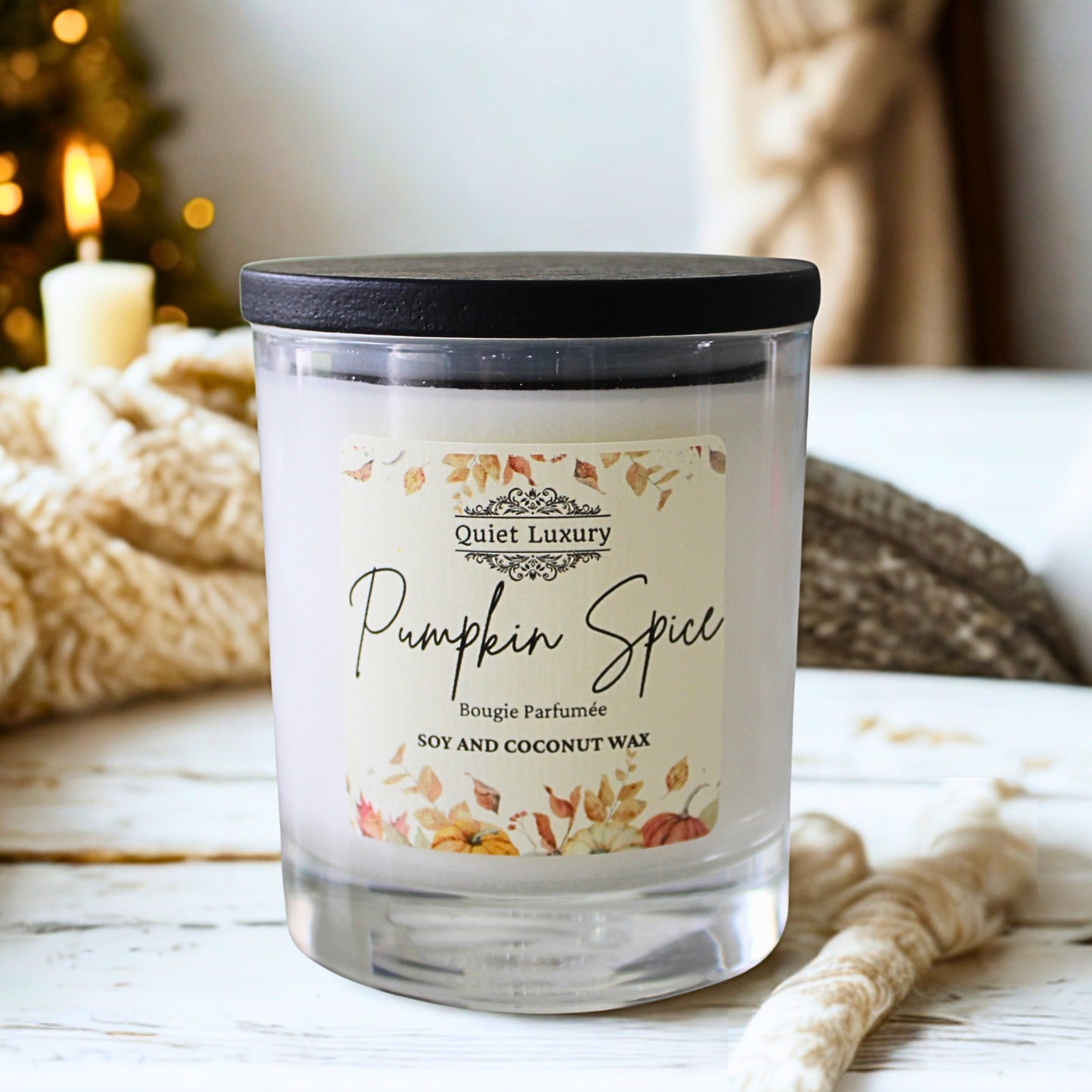 Candle labeled 'Pumpkin Spice' by Quiet Luxury on a wooden surface with a blurred background.