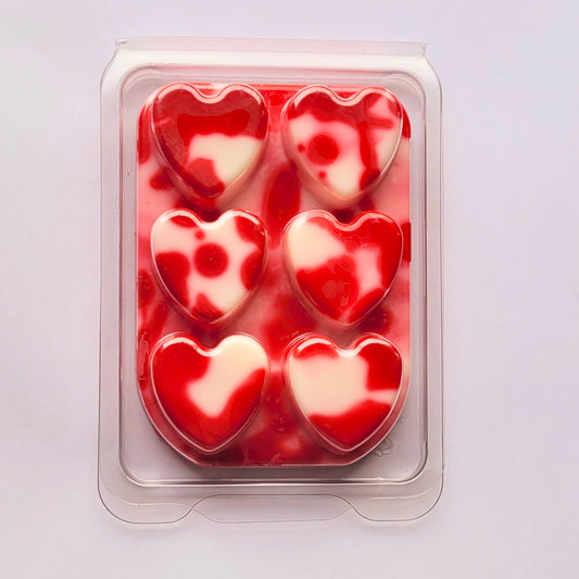 Packaged heart-shaped red and white candies on a light purple background