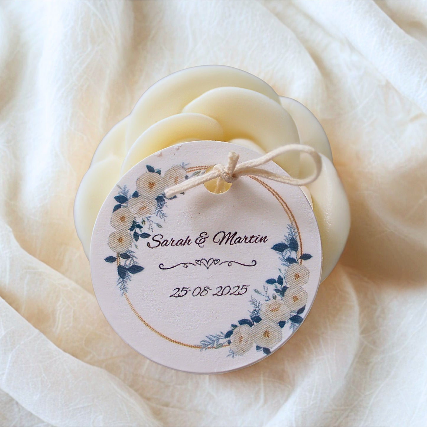 candle wedding favour with a decorative tag featurin personalised tag, on a soft white fabric background.