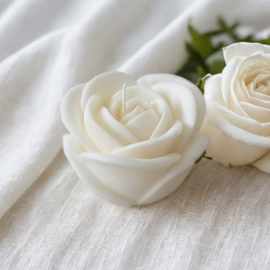 Two white rose wedding favours on a textured white fabric background
